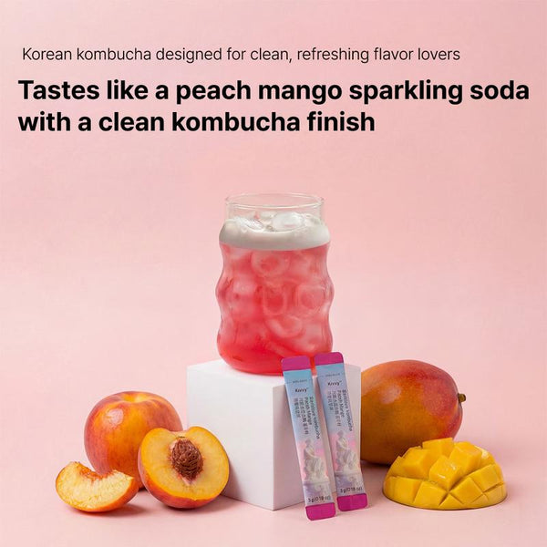 Glass of peach mango kombucha with stick packs and fresh fruit